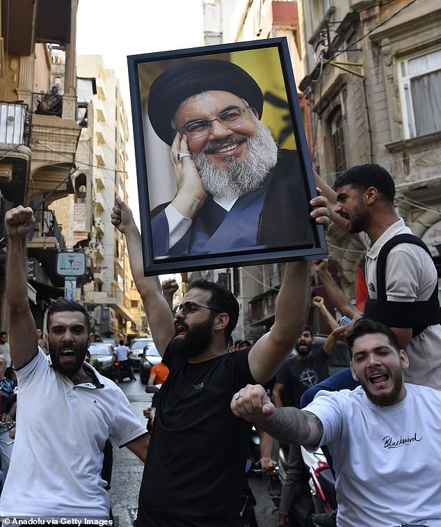 Um grupo se reúne carregando o pôster de Nasrallah e entoando slogans em Beirute no sábado