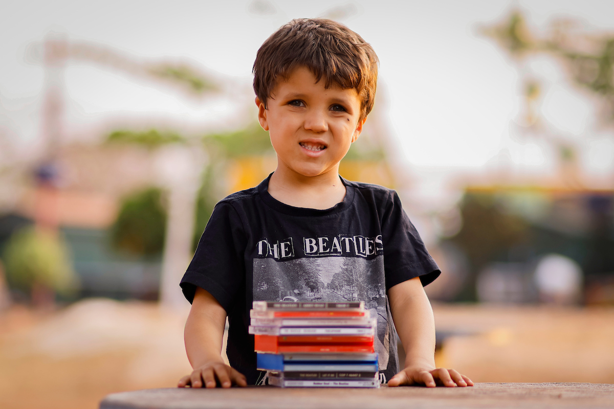 Foto colorida de um menino com blusa dos Beatles - Metrópoles