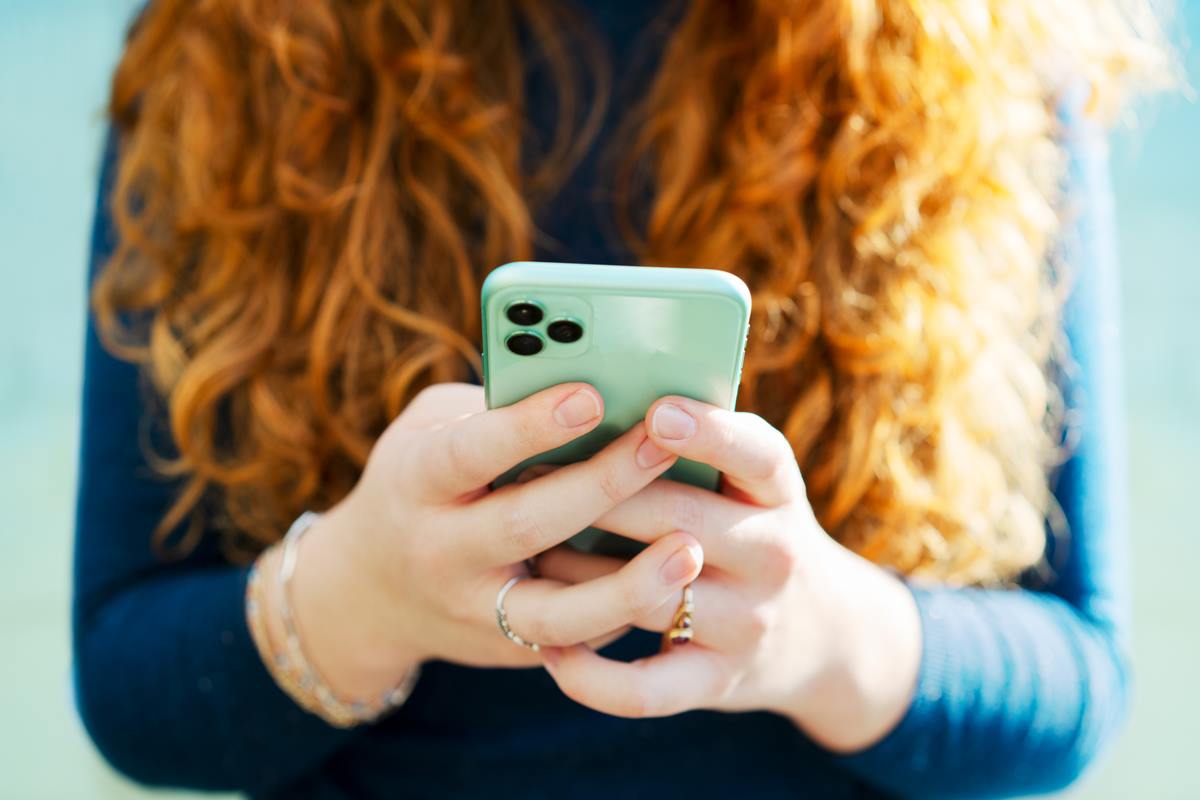 Foto colorida de uma mulher com celular - Metrópoles