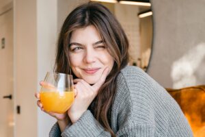 Foto colorida de mulher tomando suco de laranja - Metrópoles