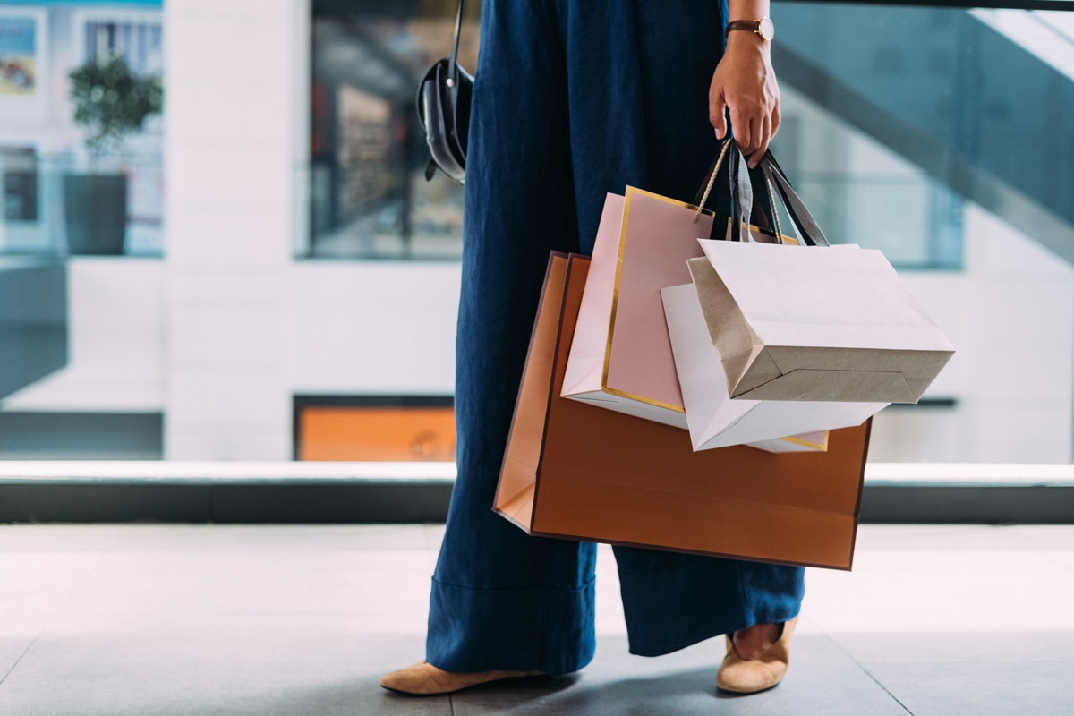 Uma mulher branca parada no shopping com sacolas de papel. Sacolas compras shopping black friday ofertas roupas novas roupa nova