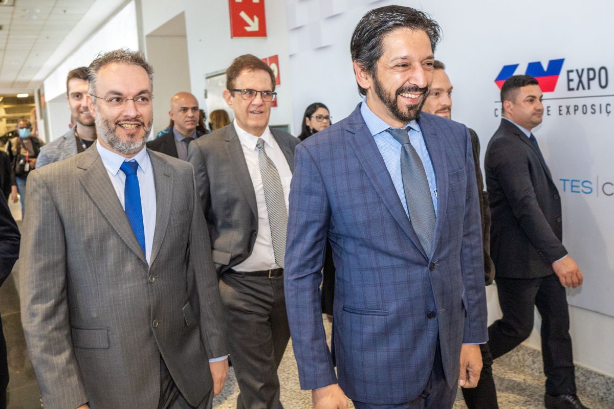 imagem colorida mostra ricardo nunes e fernando padula andando na bienal do livro