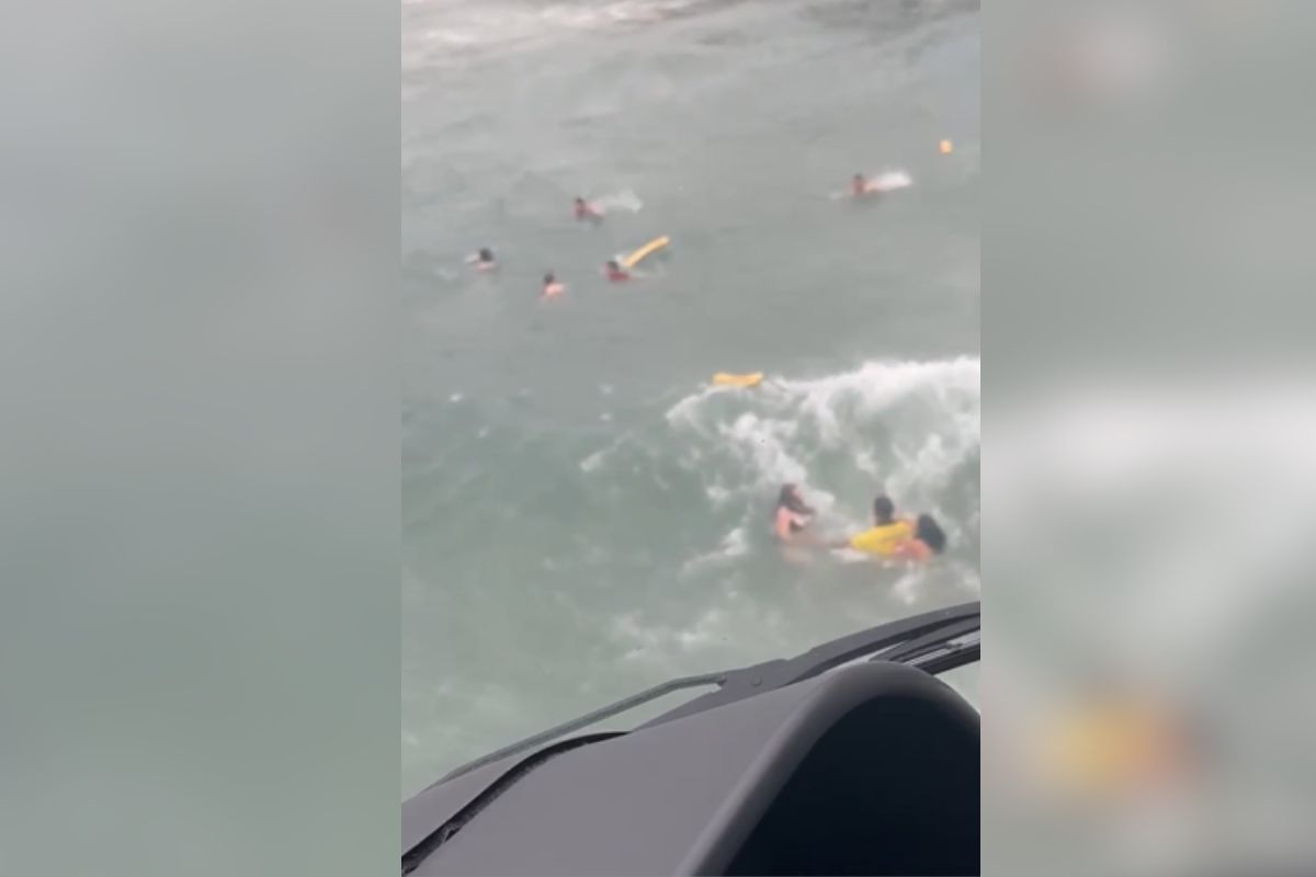 imagem colorida mostra salva-vidas resgatando grupo de banhistas de afogamento no mar de ubatuba