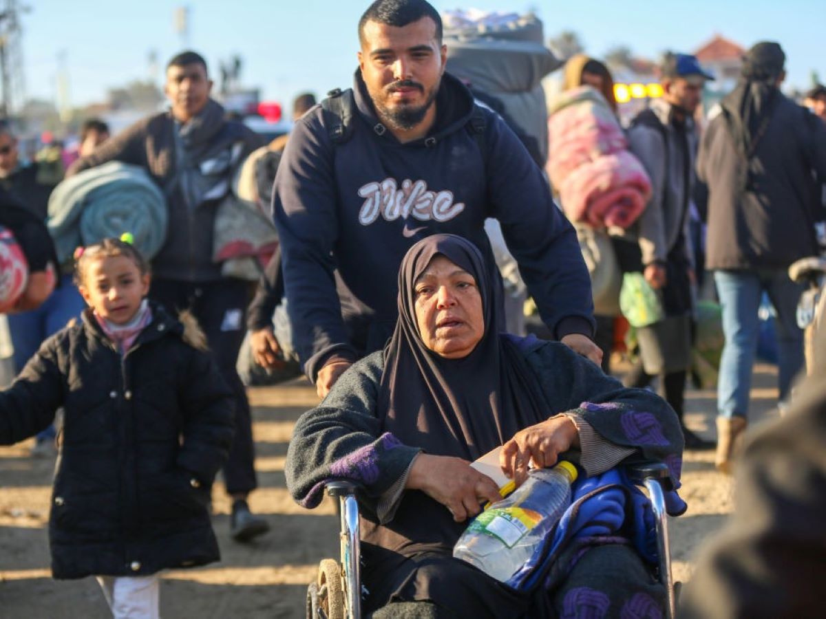 Uma mulher idosa em cadeira de rodas avança com a ajuda de um homem enquanto dezenas de milhares de palestinos, deslocados pelas forças de Israel, retornam às suas casas pela rua Al-Rashid, na faixa costeira, após o acordo de cessar-fogo na cidade de Gaza -Metrópoles